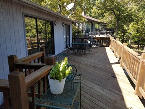 A wooden deck with outdoor seating, including a table and chairs, and a potted plant.