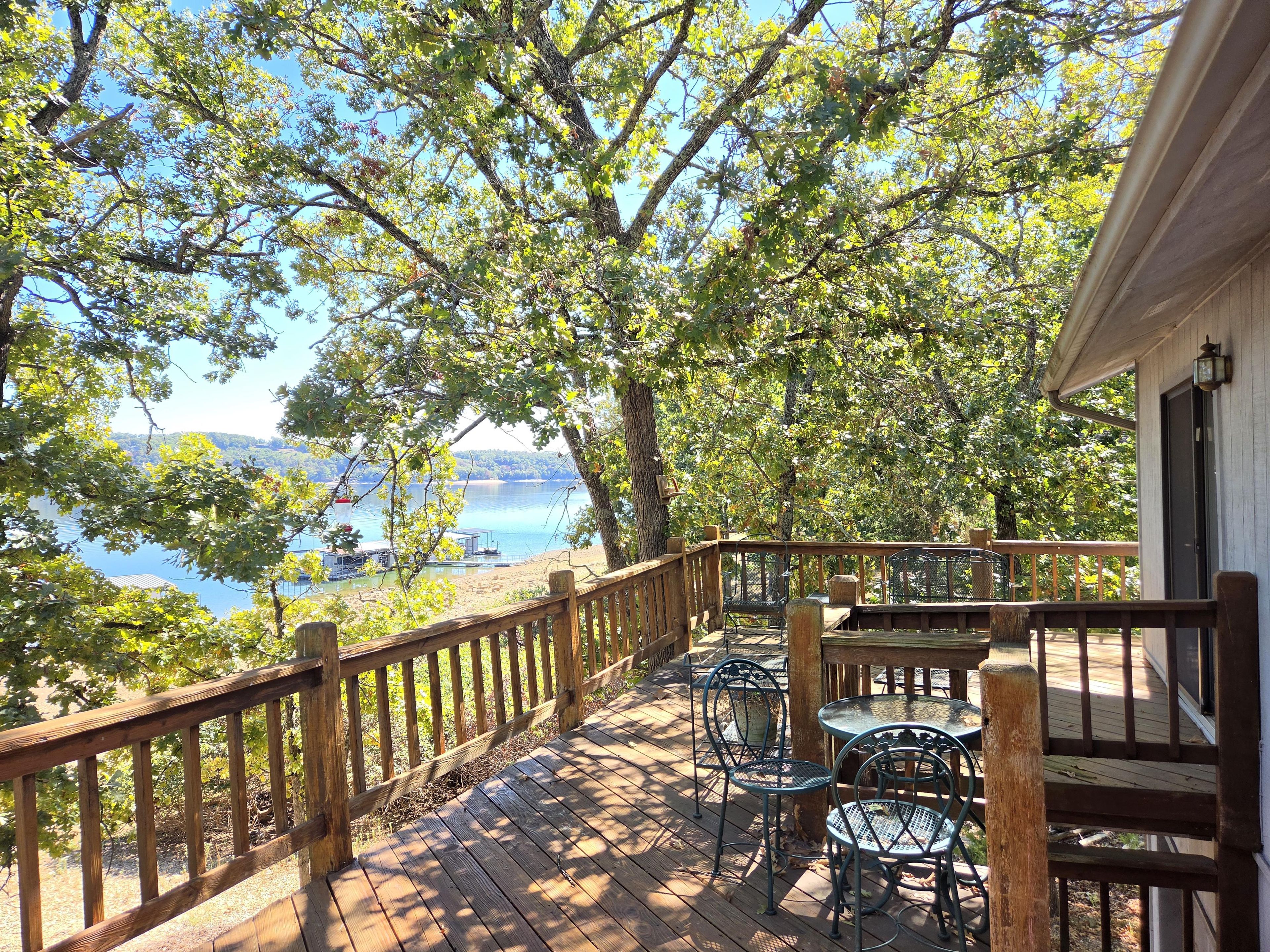 A wooden deck with outdoor furniture overlooking a lake.