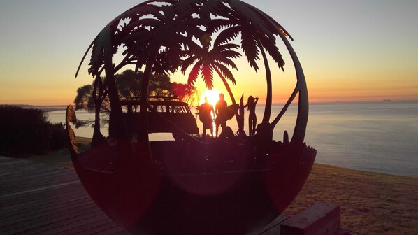 Une sculpture sphérique représentant des palmiers, avec un coucher de soleil en arrière-plan.