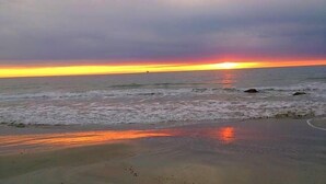 Een strand met golven en een zonsondergang.