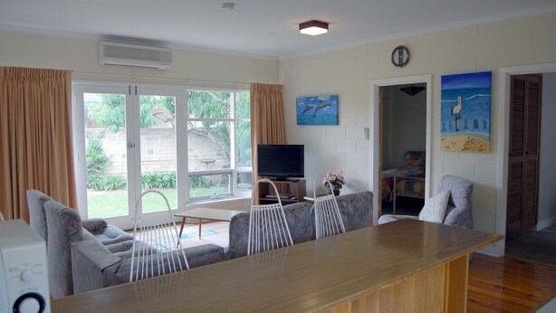 Een woonkamer met een houten tafel, twee banken, een televisie en een schilderij van dolfijnen.