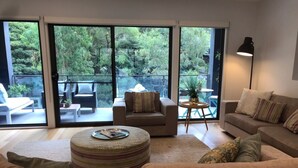 A spacious living room with a large sliding glass door leading to an outdoor patio area. - The Boulevard House Lorne (Lorne)