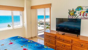 Habitación de hotel con cama, televisión, muebles de madera y vista al mar.