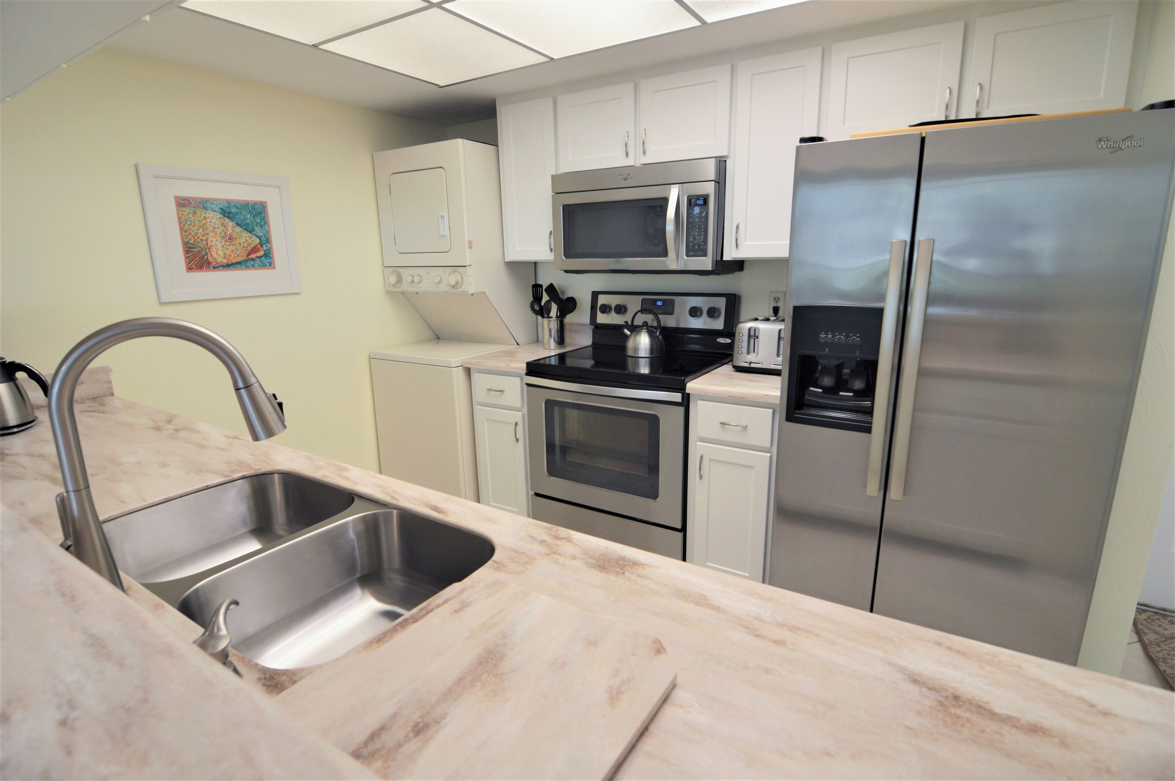 A modern kitchen with stainless steel appliances, a double sink, and white cabinetry.