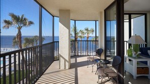 A balcony with a view of the ocean, palm trees, and a seating area with chairs and a table. - Sanibel Harbour Resort Harbour Tower 211:    Boasting amazing sunset views from the lanai (Fort Myers)
