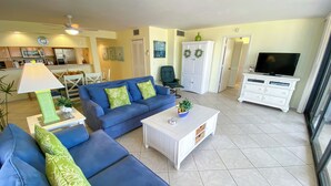 A living room with a blue sofa, a coffee table, and a TV. - Sanibel Harbour Resort Harbour Tower 211:    Boasting amazing sunset views from the lanai (Fort Myers)