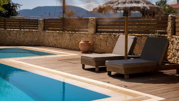 A pool area with lounge chairs and a thatched umbrella.