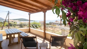 A covered outdoor seating area with wooden tables and chairs, overlooking a scenic landscape.