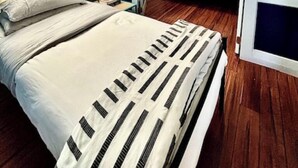 Une chambre à coucher avec un lit, une table de chevet, une lampe et une fenêtre.