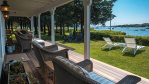 Un espace extérieur aménagé, abrité et doté de meubles en osier, d’une terrasse en bois et d’une vue sur l’eau et les bateaux.