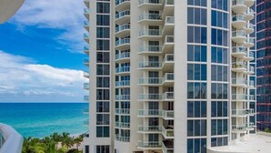 A high-rise hotel with multiple balconies overlooking a beach.