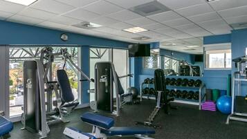Un gimnasio con diverso equipo de ejercicio, que incluye máquinas de pesas, bancos y mancuernas.