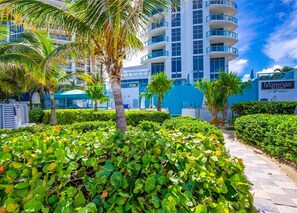 A resort with a modern building, palm trees, and well-maintained gardens.