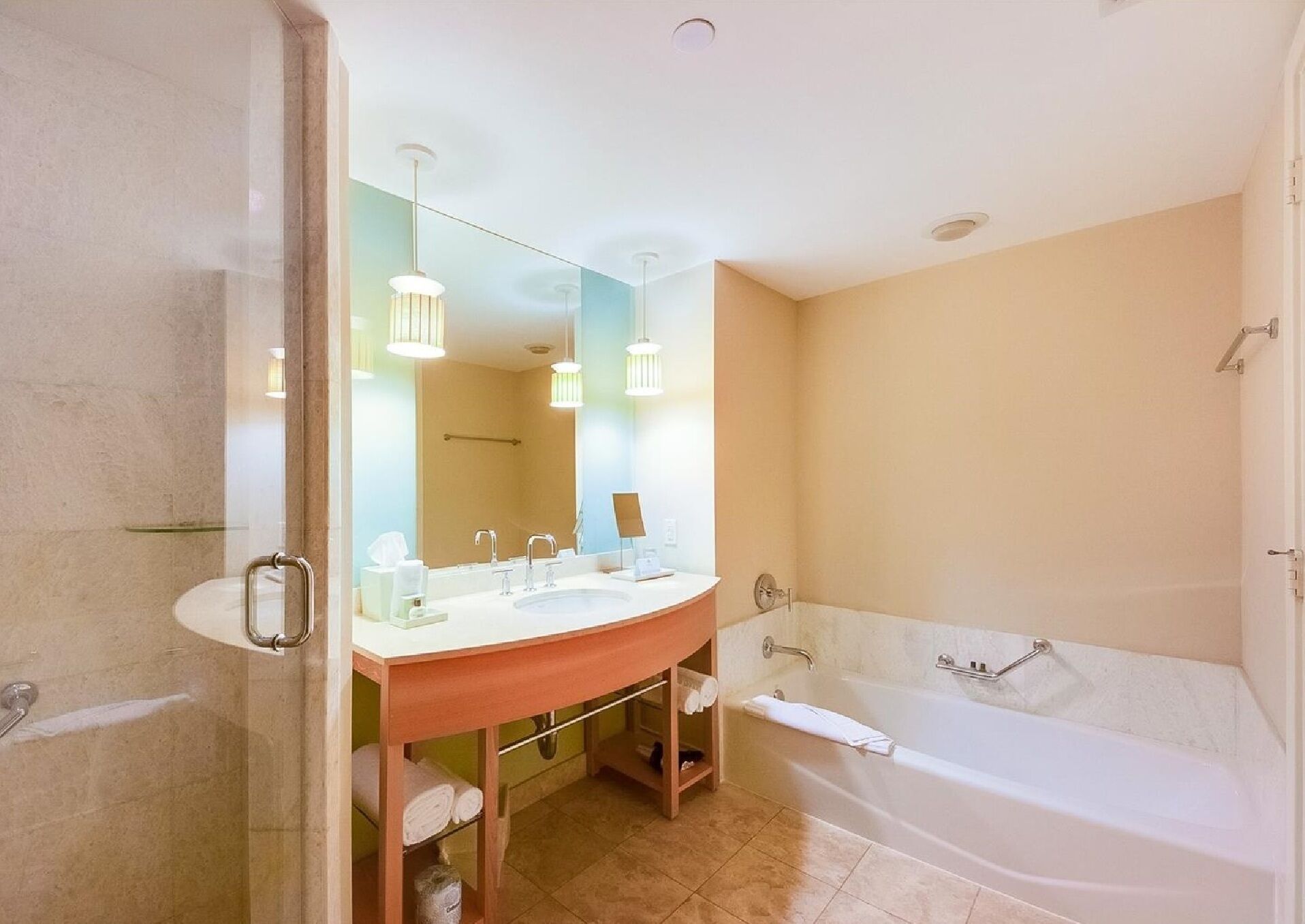 Une salle de bain avec un meuble-lavabo à deux vasques, un grand miroir, une baignoire et un espace douche.