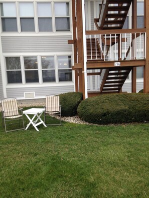 A residential building with a wooden staircase, a small patio with a table and chairs, and a well-maintained hedge. - Escape to the Lake!      (Port Clinton)