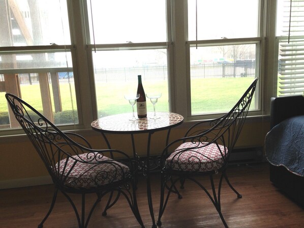 A dining area with a round table and four chairs, a bottle of wine, and two wine glasses. - Escape to the Lake!      (Port Clinton)