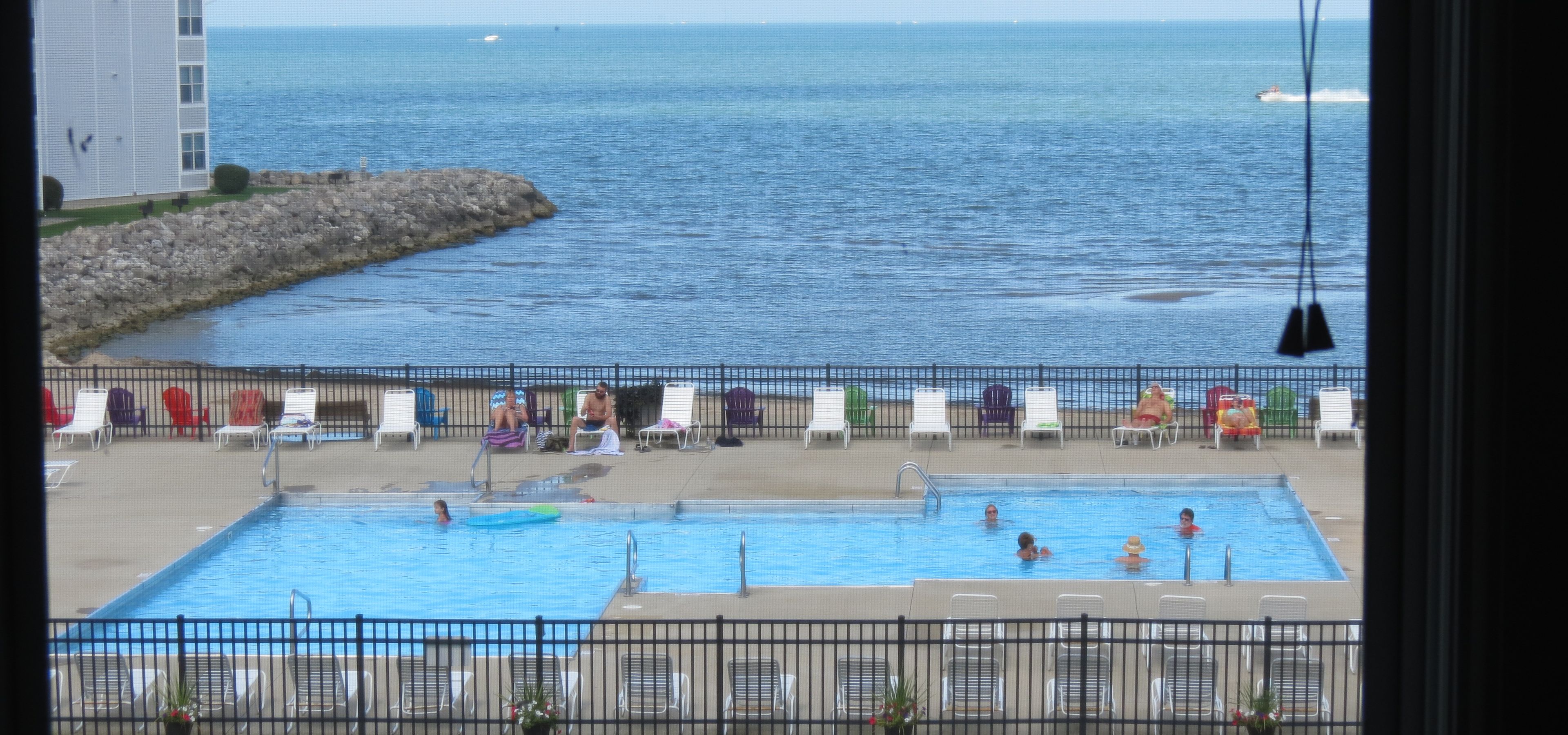 A swimming pool with lounge chairs and a view of the sea.