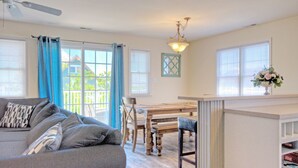 Ein gemütliches Wohnzimmer mit grauem Sofa, einem Holzesstisch und einem Deckenventilator.