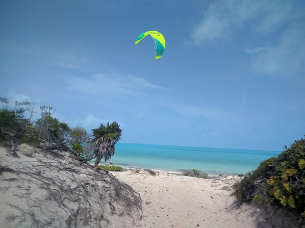 A beach with a clear sky, a sandy path, and a person flying a kite. - Sea La Vie - Beachside Studio Unit #3 (Long Bay Hills)