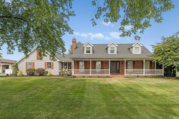 A two-story house with a front porch, brick exterior, and a well-maintained lawn. - Harvest Drive Family Getaway in Heart of Amish Farm Country (Gordonville)