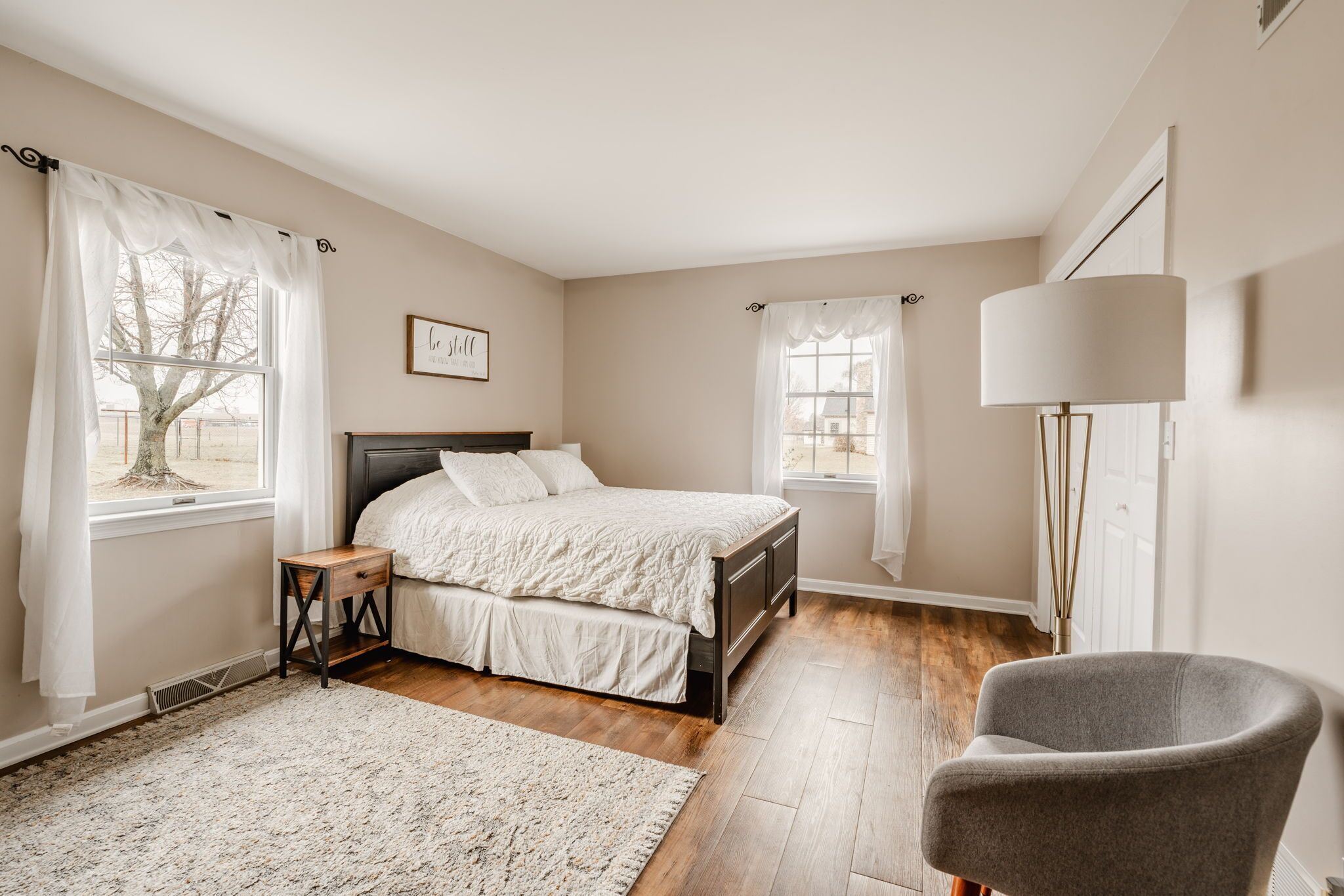 Une chambre à coucher avec un lit, une chaise, une table de chevet et une lampe.