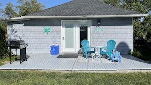 Una casa con veranda, barbecue e due poltrone Adirondack.