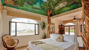 A bedroom with a large bed, a rocking chair, a window with a view of the beach, and a mural on the ceiling. - Villa Umakiha, Secluded Beach Villa with Private Pool + Jacuzzi! (Playa Del Carmen)