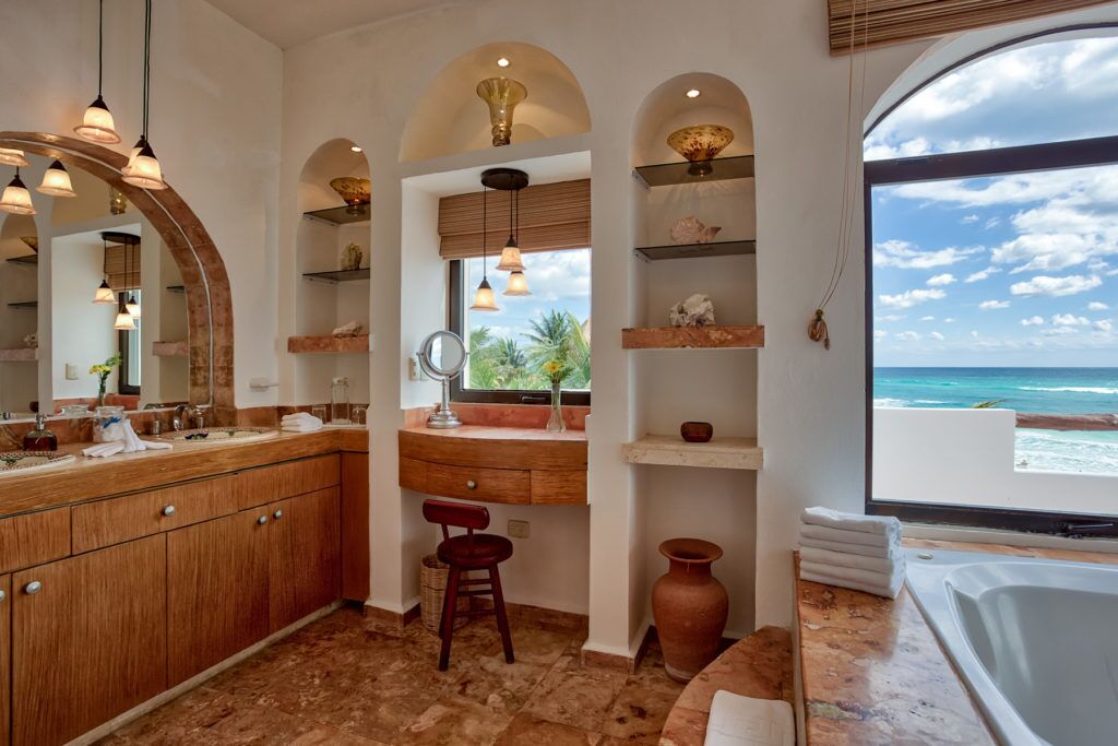 A bathroom with a large vanity, a bathtub, and a view of the ocean.