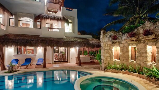 A modern hotel with a pool, lounge chairs, and a thatched-roof structure. - Villa Umakiha, Secluded Beach Villa with Private Pool + Jacuzzi! (Playa Del Carmen)