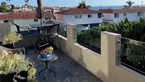 A rooftop terrace with a table and chairs, potted plants, and a view of the sea and buildings. - Ocean View!  4 Minute Walk To Beach!  Walk to Everything! (San Clemente)