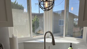 A kitchen with a stainless steel sink, a modern faucet, and a hanging light fixture. - Ocean View!  4 Minute Walk To Beach!  Walk to Everything! (San Clemente)