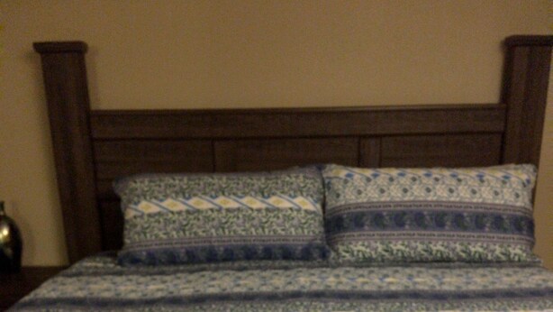 Una cama con una colcha estampada y dos almohadas.