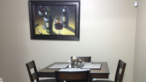 Un comedor con una mesa, sillas, una alfombra y un cuadro en la pared.