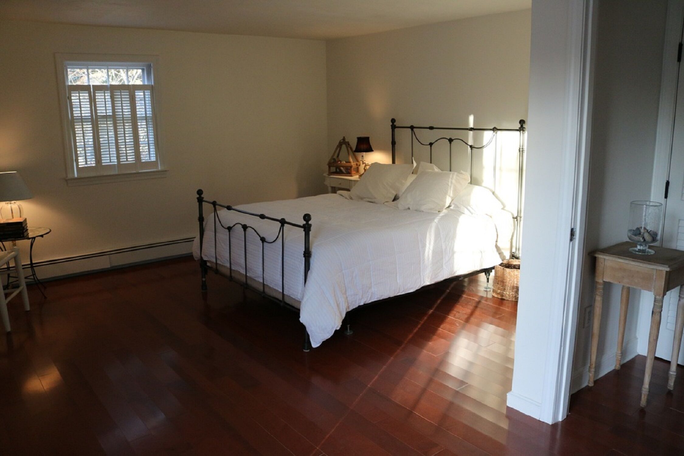 A bedroom with a bed, a nightstand, a lamp, and a window.