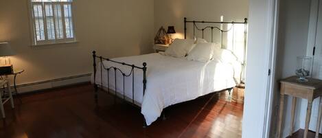 A bedroom with a bed, a nightstand, a lamp, and a window.