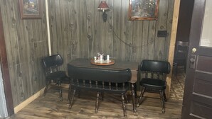A dining area with a wooden wall, a round table, and two chairs. - Piedmont lake hunting and fishing cabin (Freeport)