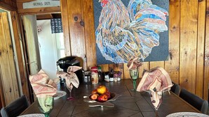 Una mesa de madera con una pintura de gallo, un cuenco de fruta y un menú.