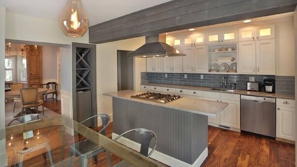 Una cocina moderna con una isla central, electrodomésticos de acero inoxidable y un comedor con mesa y sillas de vidrio.