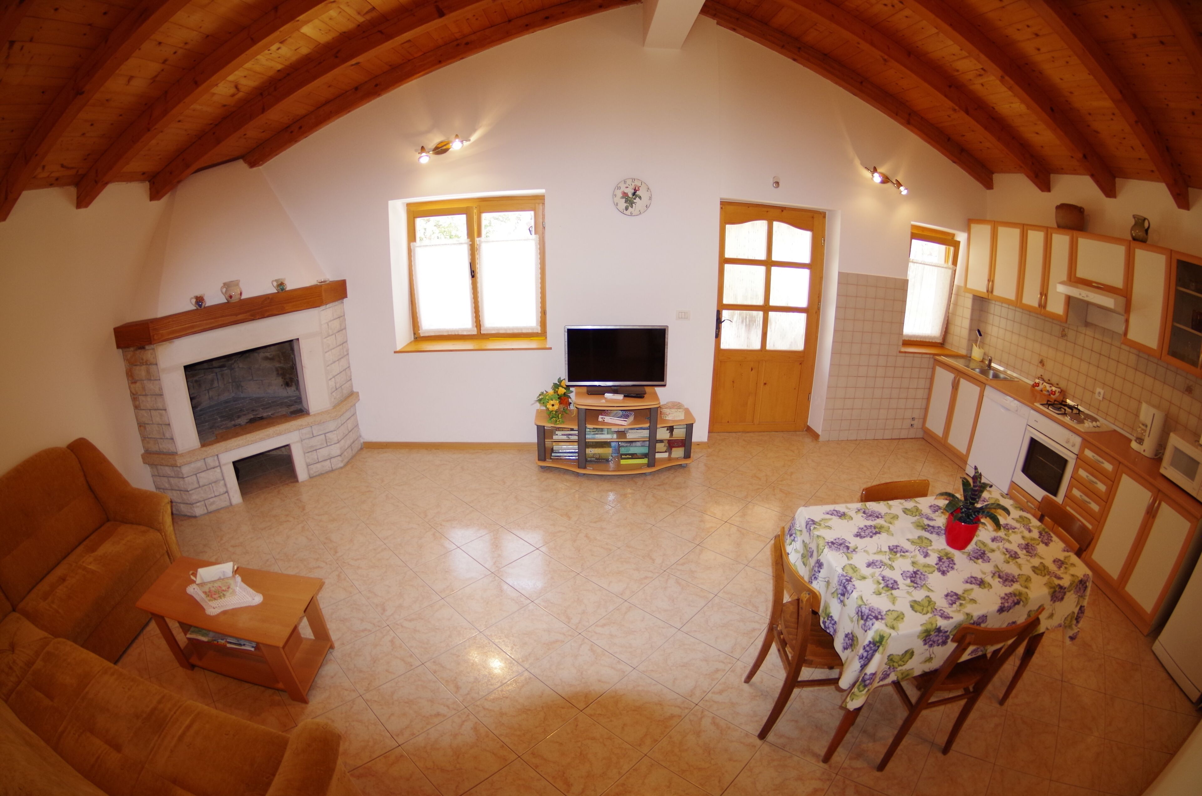 Una sala de estar acogedora con chimenea, televisor y comedor con mesa dispuesta para dos.