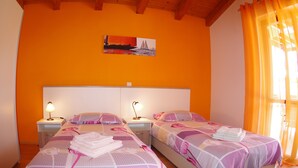 Una stanza con due letti, ognuno dotato di testiera, comodini con lampade e un quadro appeso al muro.