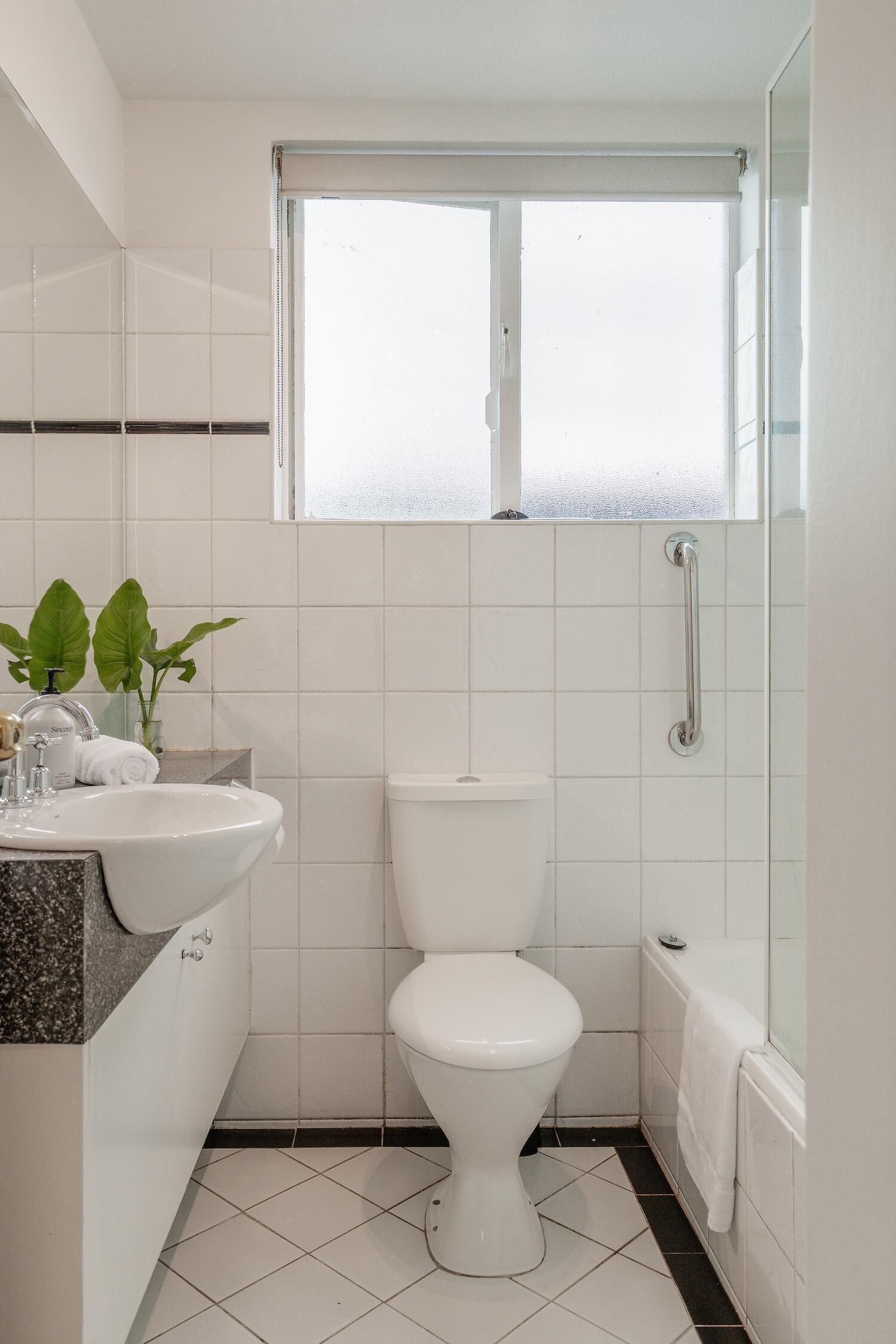 Ein kleines Badezimmer mit Toilette, Waschbecken und einem Fenster über der Toilette.