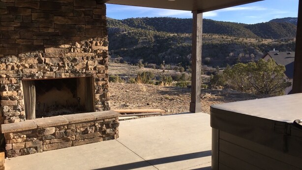 Eine Terrass mit Kamin aus Stein, Betonboden und Blick auf eine hügelige Landschaft.