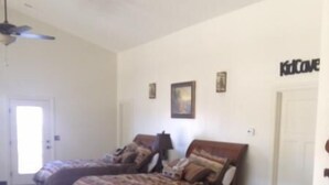 Ein Schlafzimmer mit zwei Betten, einem Deckenventilator und einer Tür.