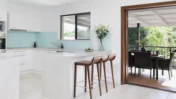 A modern kitchen with white cabinetry, a large island with stools, and a view of an outdoor patio with dining furniture.