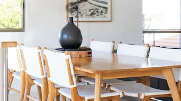A dining area with a wooden table and chairs, a black vase, and a framed picture on the wall.