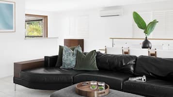 A modern living room with a black leather sofa, a wooden coffee table, and a potted plant.