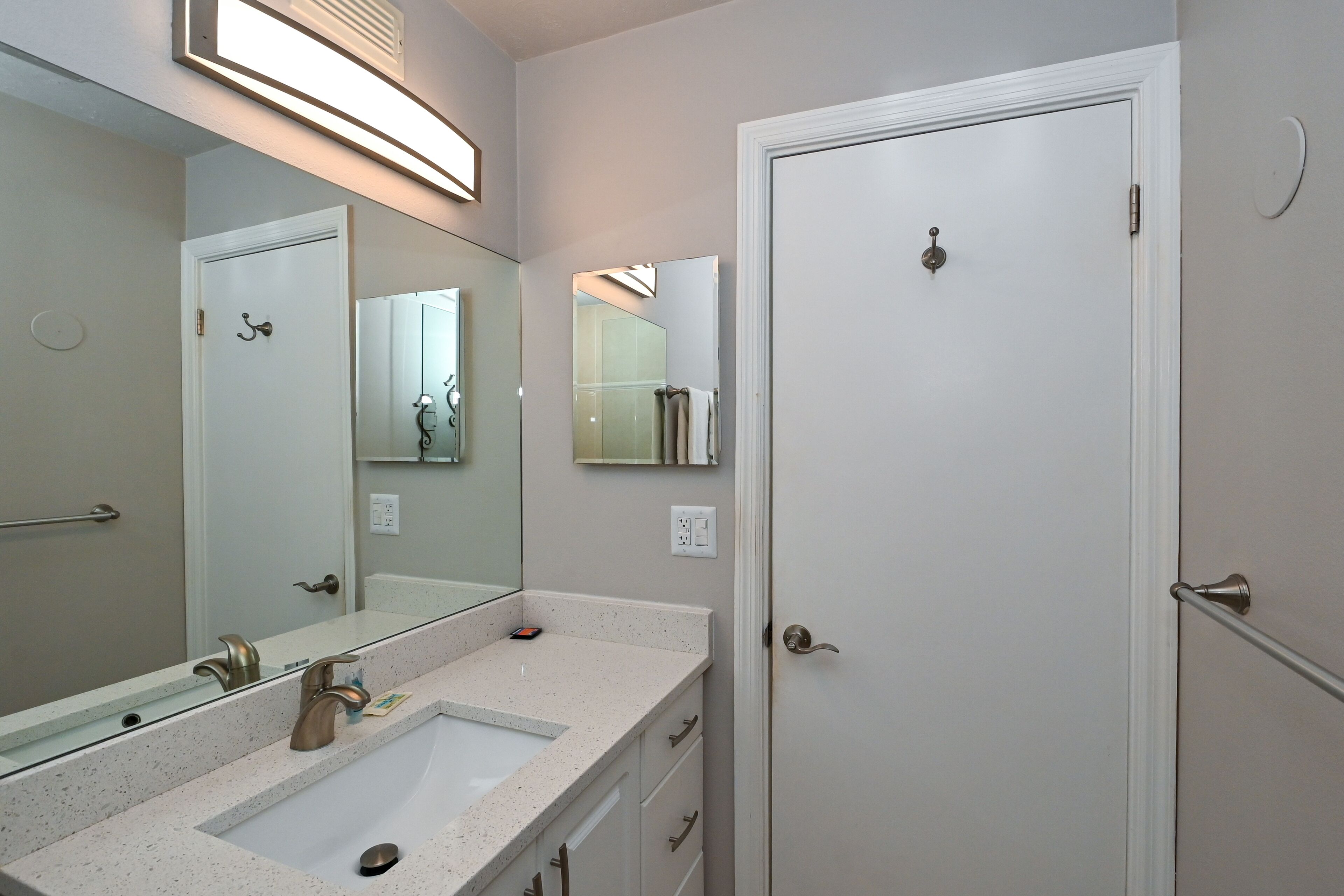 A bathroom with a double sink, a large mirror, and a white door.