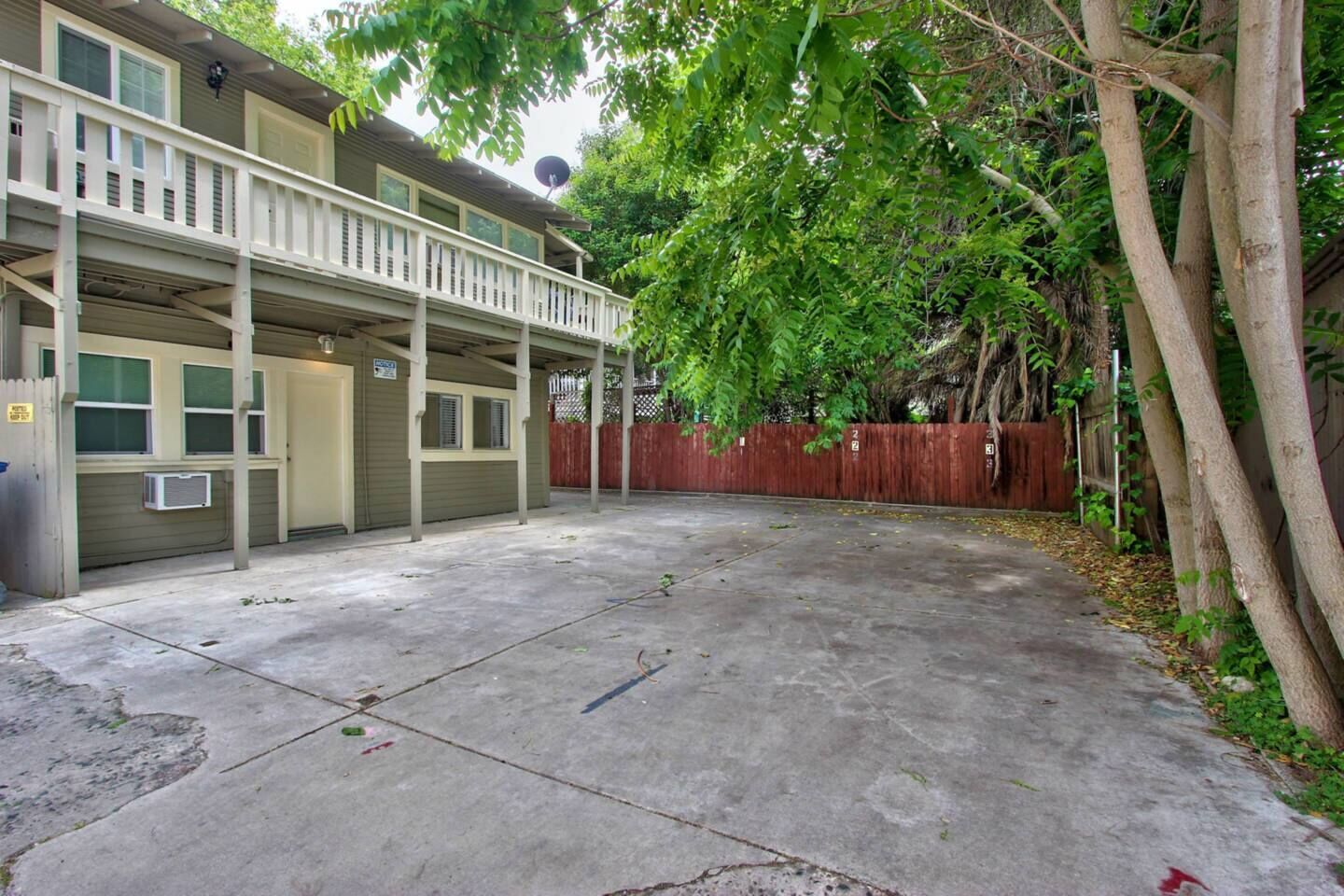 A two-story house with a covered patio, a fenced backyard, and a satellite dish.
