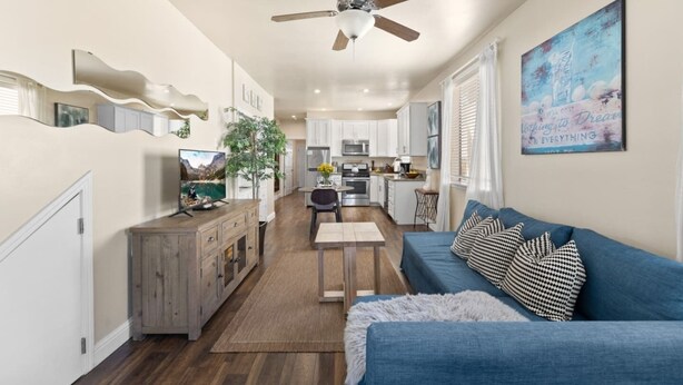 Un salon moderne avec un canapé bleu, un meuble en bois et un ventilateur de plafond.