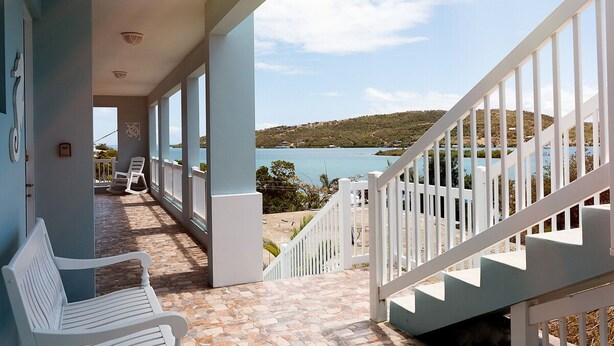 Ein Balkon mit Meerblick, eine weiße Bank und eine Treppe.